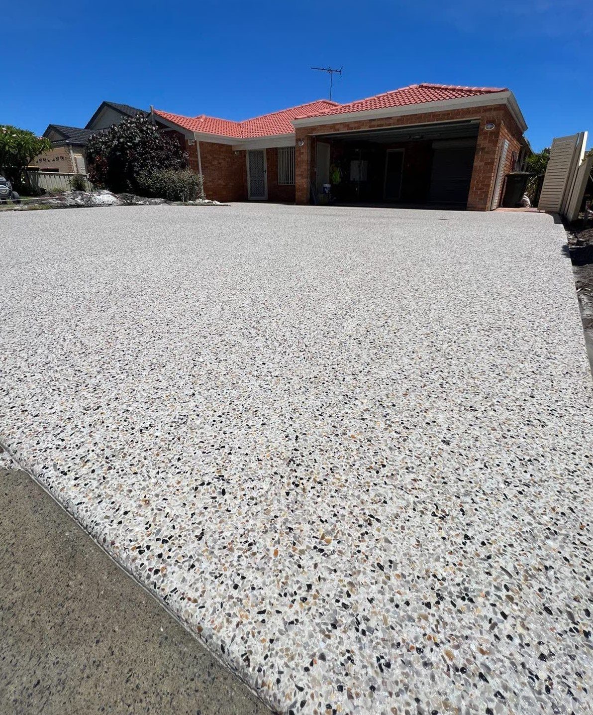 Exposed aggregate driveway across a full frontage after washing and sealing